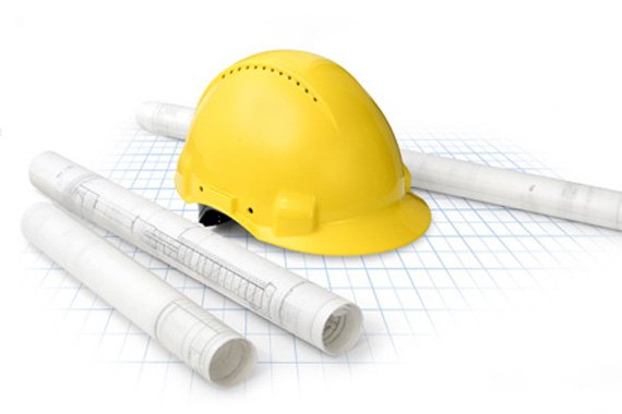 hard hat with blueprint rolls set on graph paper