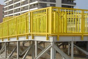 Yellow fiberglass handrail system mounted on a public beach access ramp